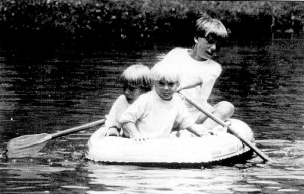 Three young boys sit in a rowboat.