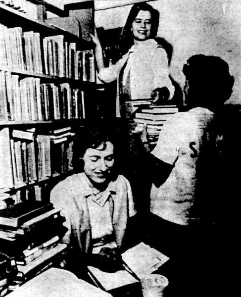 Three women shelve books at a library