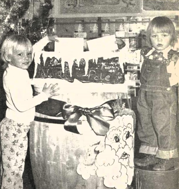 Two young children mail letters to Santa.