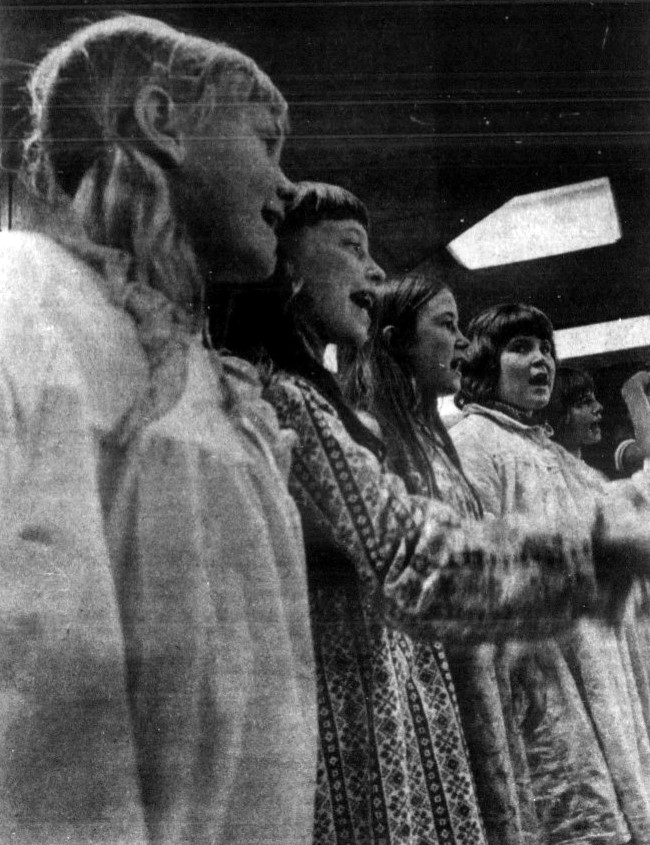 5 girls in nightgowns sing at a holiday concert.