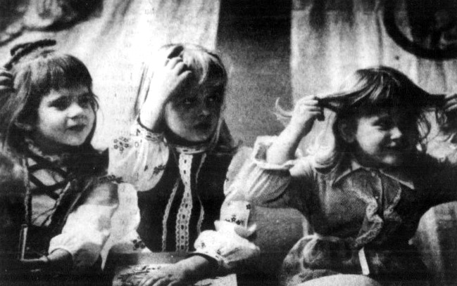 Three young girls touch their hair as part of a play.