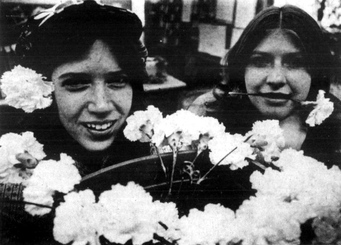 Two young women wear carnations that they are selling for in a high school fundraiser.