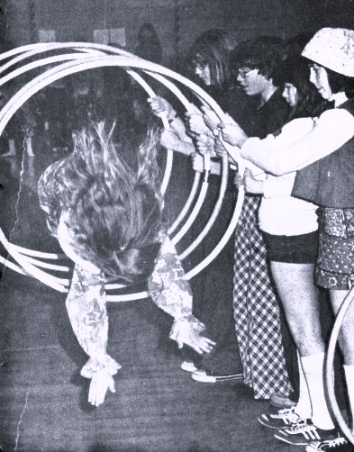 A girl dives through several hula hoops held by other children.