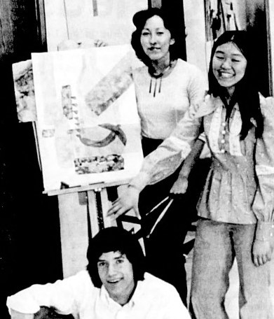 Three high school students pose with an easel displaying artwork.