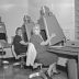 Black and white photo of two women dressed in 1950's clothing and hair styles, sitting at old style Kodak Kodagraph microfilm readers at the Wyoming State Archives.